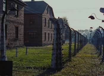 Movie still from “Night and Fog” (1956), directed by Alain Resnais – A row of barbed wire fences in a field; Extreme Wide shot, High angle
