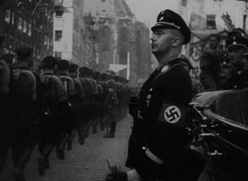 Movie still from “Night and Fog” (1956), directed by Alain Resnais – An old photo of a man in a military uniform; Medium shot, Low angle