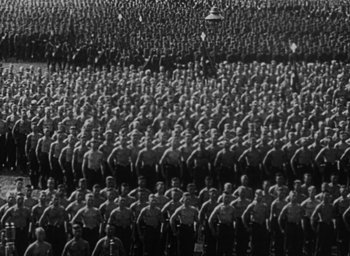 Movie still from “Night and Fog” (1956), directed by Alain Resnais – A black and white photo of a large group of men in uniform; Extreme Wide shot, High angle