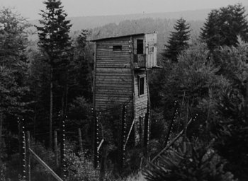 Movie still from “Night and Fog” (1956), directed by Alain Resnais – An outhouse in the middle of a forest; Extreme Wide shot, Low angle