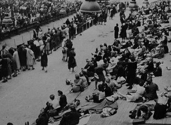 Movie still from “Night and Fog” (1956), directed by Alain Resnais – A crowd of people sitting and standing on the ground; Extreme Wide shot, High angle
