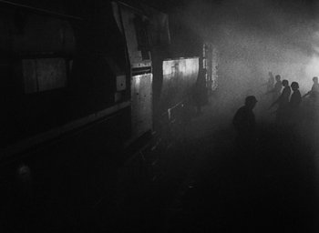 Movie still from “Night and Fog” (1956), directed by Alain Resnais – A man standing next to a train on a train track; Extreme Wide shot, High angle