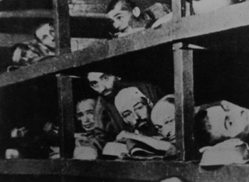 Movie still from “Night and Fog” (1956), directed by Alain Resnais – A black and white photo of a group of people in bunkbeds; Wide shot, Overhead angle