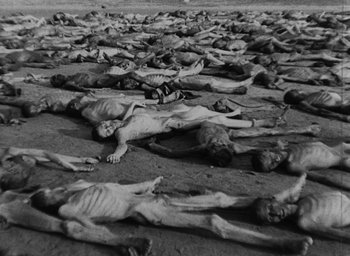 Movie still from “Night and Fog” (1956), directed by Alain Resnais – A large group of dead bodies laying on the ground; Extreme Wide shot, High angle