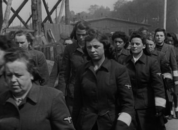 Movie still from “Night and Fog” (1956), directed by Alain Resnais – Black and white photograph of a group of women in uniforms; Medium shot, High angle