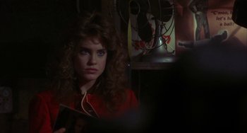 Movie still from “Night of the Comet” (1984), directed by Thom Eberhardt – A woman with curly red hair is listening to music; Close Up shot, Over the shoulder angle