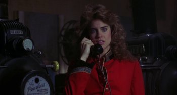 Movie still from “Night of the Comet” (1984), directed by Thom Eberhardt – A woman talking on a phone while wearing a red jacket; Close Up shot, Low angle