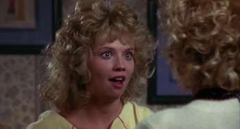 Movie still from “Night of the Comet” (1984), directed by Thom Eberhardt – A young woman with blonde curly hair looking into a mirror; Close Up shot, Over the shoulder angle