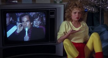 Movie still from “Night of the Comet” (1984), directed by Thom Eberhardt – A woman sitting in front of a television; Medium shot, Over the shoulder angle