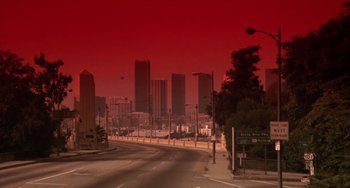 Movie still from “Night of the Comet” (1984), directed by Thom Eberhardt – A city street with a red sky and buildings in the background; Extreme Wide shot, High angle