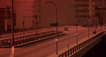 Movie still from “Night of the Comet” (1984), directed by Thom Eberhardt – A car driving down a street next to a street light; Extreme Wide shot, High angle