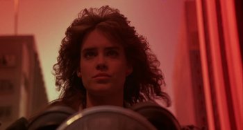 Movie still from “Night of the Comet” (1984), directed by Thom Eberhardt – A woman with long curly red hair is looking at the camera; Close Up shot, Low angle