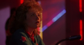 Movie still from “Night of the Comet” (1984), directed by Thom Eberhardt – A woman with red hair and a red star on her shirt; Close Up shot, Low angle