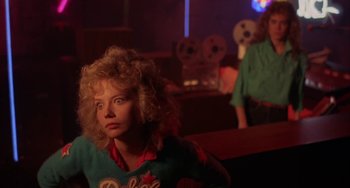 Movie still from “Night of the Comet” (1984), directed by Thom Eberhardt – A woman sitting in front of a mirror in a room; Medium shot, Over the shoulder angle