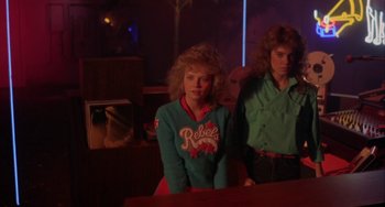 Movie still from “Night of the Comet” (1984), directed by Thom Eberhardt – A woman sitting next to another woman in a room; Medium shot, Low angle
