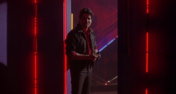 Movie still from “Night of the Comet” (1984), directed by Thom Eberhardt – A man standing in front of a red light; Medium shot, Low angle