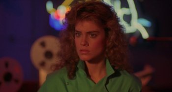 Movie still from “Night of the Comet” (1984), directed by Thom Eberhardt – A person with curly hair wearing a green shirt; Close Up shot, Low angle