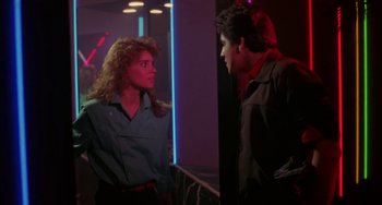 Movie still from “Night of the Comet” (1984), directed by Thom Eberhardt – A man and a woman are talking in a room; Medium shot, Over the shoulder angle