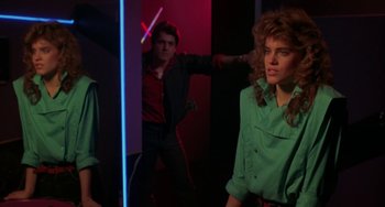 Movie still from “Night of the Comet” (1984), directed by Thom Eberhardt – A man and a woman are standing in front of a mirror; Medium shot, Over the shoulder angle