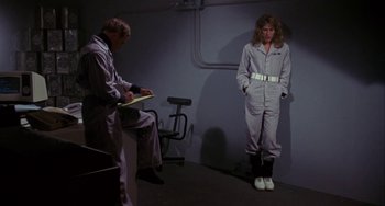 Movie still from “Night of the Comet” (1984), directed by Thom Eberhardt – A man and a woman are standing next to each other in a room; Wide shot, Low angle