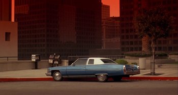 Movie still from “Night of the Comet” (1984), directed by Thom Eberhardt – An old car parked on the side of the street; Wide shot, Low angle