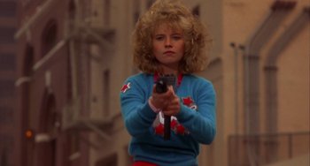 Movie still from “Night of the Comet” (1984), directed by Thom Eberhardt – A woman holding a gun in her hands; Medium shot, Low angle
