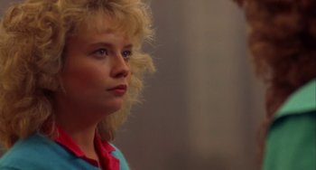 Movie still from “Night of the Comet” (1984), directed by Thom Eberhardt – A woman with blonde curly hair looking to her left; Close Up shot, Low angle