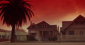 Movie still from “Night of the Comet” (1984), directed by Thom Eberhardt – A house with a red sky in the background and palm trees in the foreground; Extreme Wide shot, Low angle