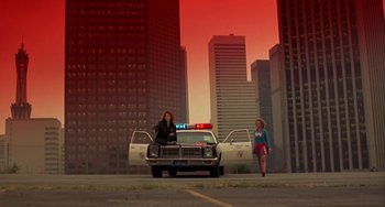 Movie still from “Night of the Comet” (1984), directed by Thom Eberhardt – Two women standing next to a white police car; Extreme Wide shot, Low angle