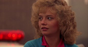 Movie still from “Night of the Comet” (1984), directed by Thom Eberhardt – A woman with blonde curly hair wearing a pink shirt; Close Up shot, Over the shoulder angle