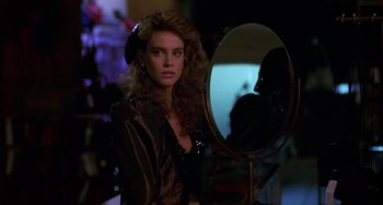 Movie still from “Night of the Comet” (1984), directed by Thom Eberhardt – A woman standing in front of a round mirror; Close Up shot, Over the shoulder angle
