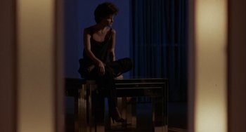 Movie still from “Night of the Comet” (1984), directed by Thom Eberhardt – A woman sitting on top of a wooden bench; Wide shot, Low angle