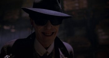 Movie still from “Night of the Comet” (1984), directed by Thom Eberhardt – A man wearing a hat and sunglasses smiling for the camera; Close Up shot, Low angle