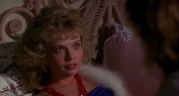 Movie still from “Night of the Comet” (1984), directed by Thom Eberhardt – A woman with blonde curly hair wearing a red necklace; Close Up shot, Over the shoulder angle