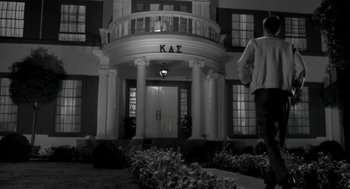 Movie still from “Night of the Creeps” (1986), directed by Fred Dekker – A person walking in front of a building with columns; Wide shot, Low angle