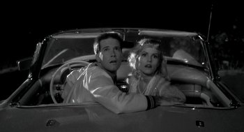 Movie still from “Night of the Creeps” (1986), directed by Fred Dekker – A man and a woman sitting in the back seat of a car; Close Up shot, Low angle
