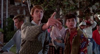 Movie still from “Night of the Creeps” (1986), directed by Fred Dekker – Two young men standing next to each other in front of a crowd; Medium shot, Low angle