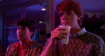 Movie still from “Night of the Creeps” (1986), directed by Fred Dekker – A man holding a cup of coffee while looking at the camera; Medium shot, Low angle