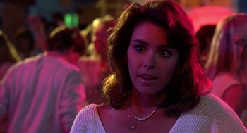 Movie still from “Night of the Creeps” (1986), directed by Fred Dekker – A person wearing a necklace in a room; Close Up shot, Over the shoulder angle