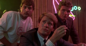 Movie still from “Night of the Creeps” (1986), directed by Fred Dekker – A man in a suit and tie next to two other men; Medium shot, Low angle