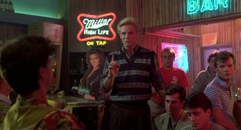 Movie still from “Night of the Creeps” (1986), directed by Fred Dekker – A group of people in a room with a neon sign; Medium shot, Over the shoulder angle