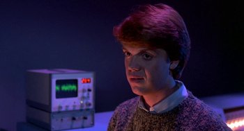 Movie still from “Night of the Creeps” (1986), directed by Fred Dekker – A young man in a sweater is sitting in front of an electronic device; Close Up shot, High angle
