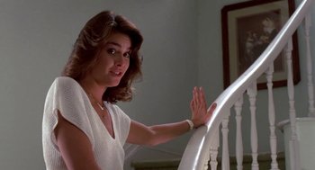 Movie still from “Night of the Creeps” (1986), directed by Fred Dekker – A woman leaning on a railing of a staircase; Medium shot, Low angle