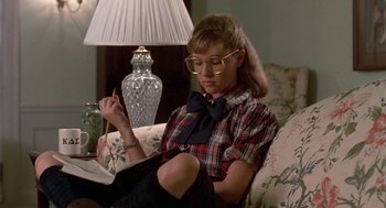 Movie still from “Night of the Creeps” (1986), directed by Fred Dekker – A woman sitting on a couch reading a book; Medium shot, High angle
