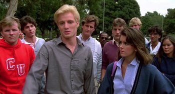 Movie still from “Night of the Creeps” (1986), directed by Fred Dekker – A group of people standing around each other in the street; Medium shot, Over the shoulder angle