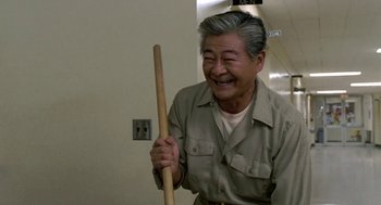 Movie still from “Night of the Creeps” (1986), directed by Fred Dekker – An older man holding a wooden stick in his hand; Medium shot, Low angle