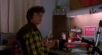 Movie still from “Night of the Creeps” (1986), directed by Fred Dekker – A young man wearing headphones is sitting at a desk; Medium shot, Low angle