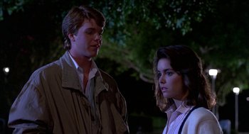 Movie still from “Night of the Creeps” (1986), directed by Fred Dekker – A man and a woman standing next to each other in the dark; Medium shot, Over the shoulder angle