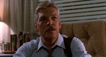 Movie still from “Night of the Creeps” (1986), directed by Fred Dekker – An older man with a mustache wearing a shirt and tie; Close Up shot, Low angle