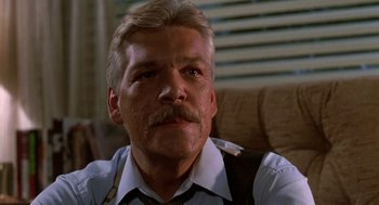 Movie still from “Night of the Creeps” (1986), directed by Fred Dekker – An older man with a mustache sitting on a couch; Close Up shot, Low angle